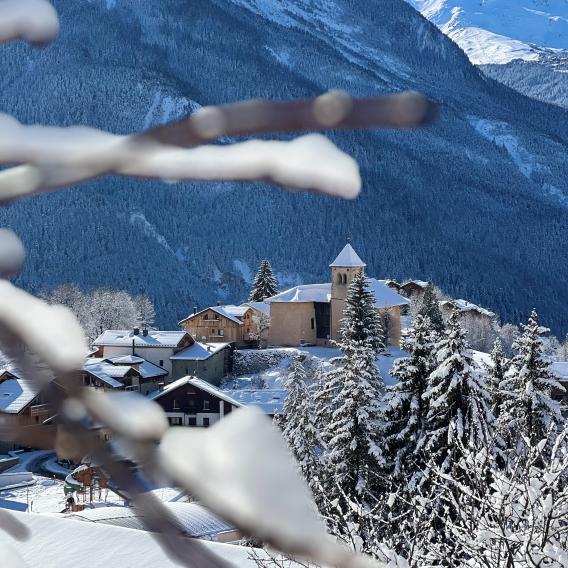 Vue sur l'eglise Saint-Sigismond, entre des branches enneigées